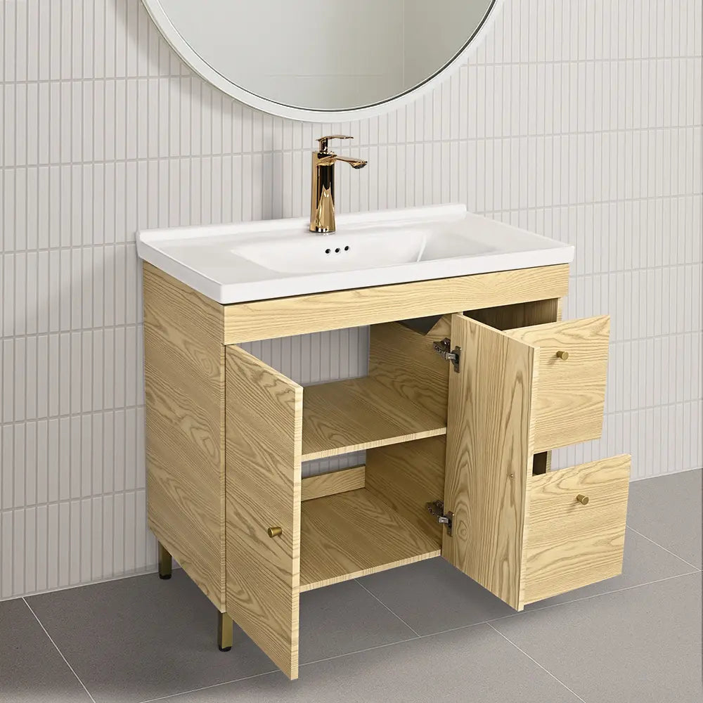 Bathroom vanity with open cabinet doors, white sink, and round mirror on tiled wall.
