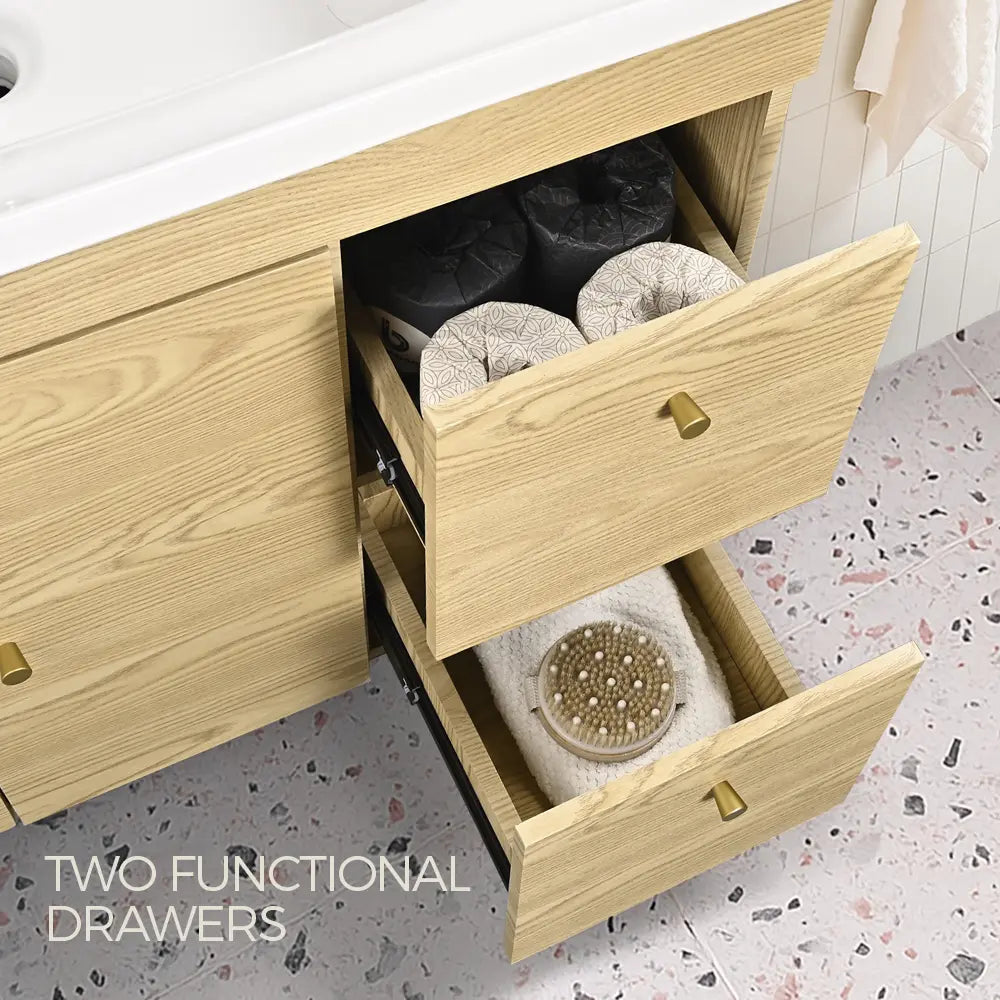 Light oak bathroom vanity with two functional storage drawers, gold handles, and white ceramic basin – modern bathroom cabinet organiser.