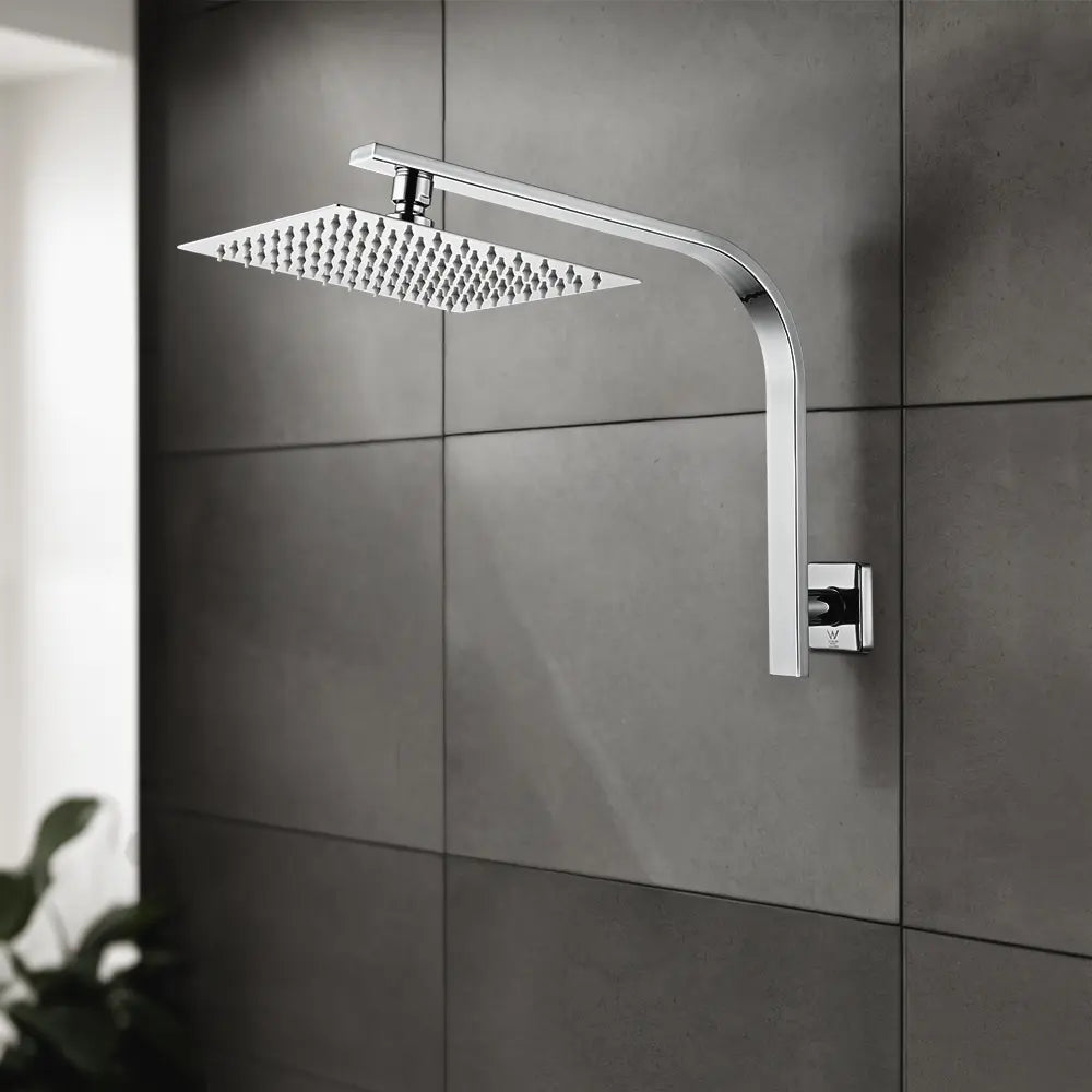 Chrome square rainfall shower head with wall-mounted arm installed on modern grey tiled bathroom wall