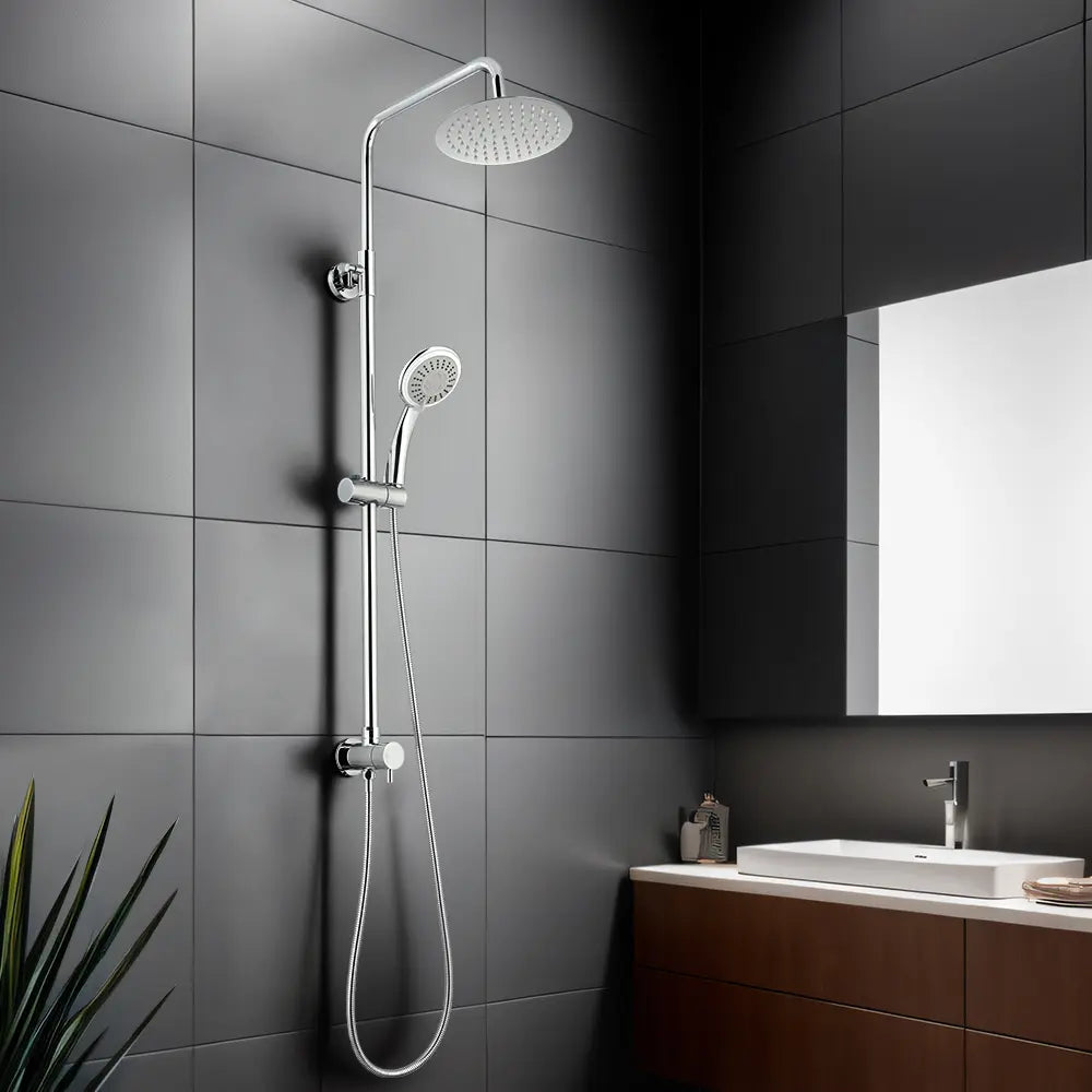 Modern chrome shower system with rainfall shower head and handheld spray installed on dark tiled bathroom wall beside vanity and mirror