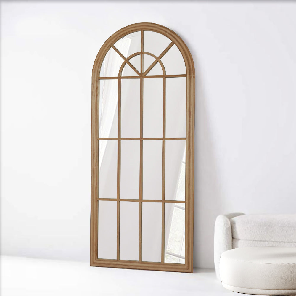 Arch-shaped mirror with wooden frame on a white wall
