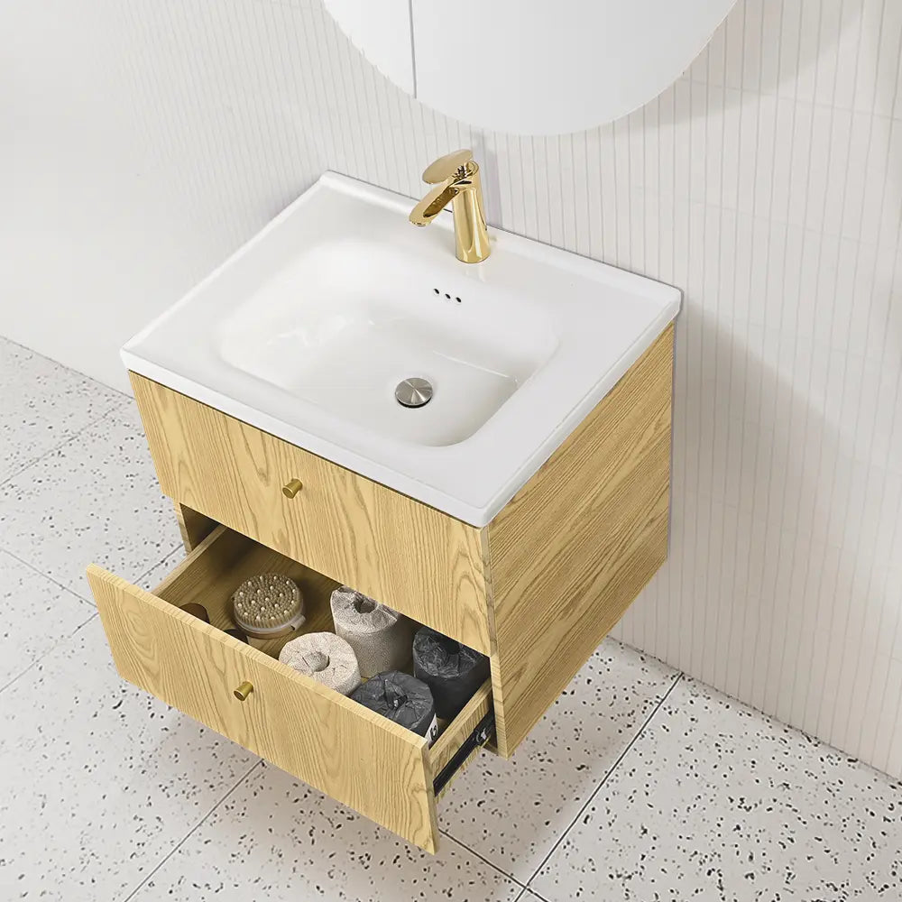 Bathroom vanity with open drawer, white sink, and gold faucet.