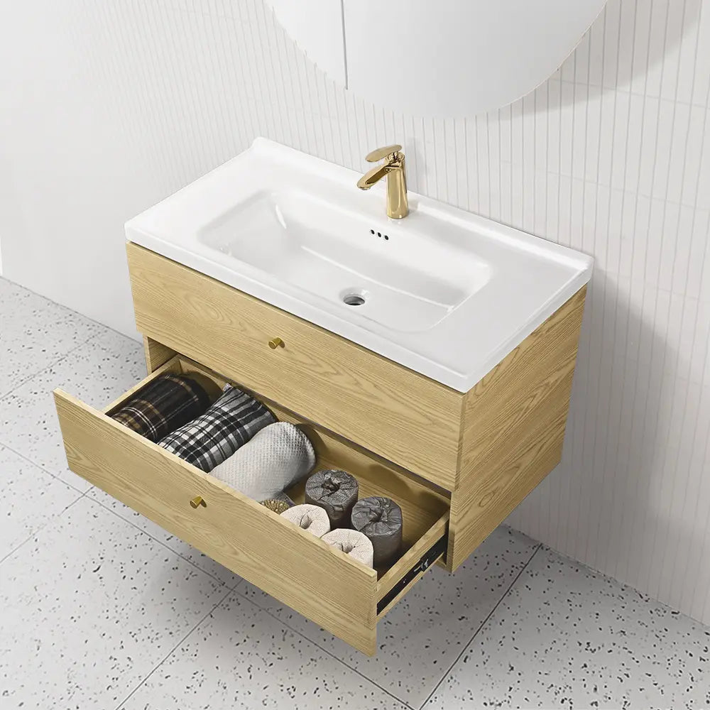 Bathroom vanity with open drawer containing towels and toiletries, gold faucet.
