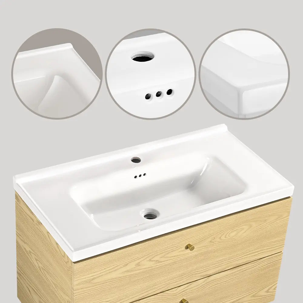White ceramic bathroom vanity basin with overflow hole and smooth edges, mounted on light oak cabinet with gold handles.