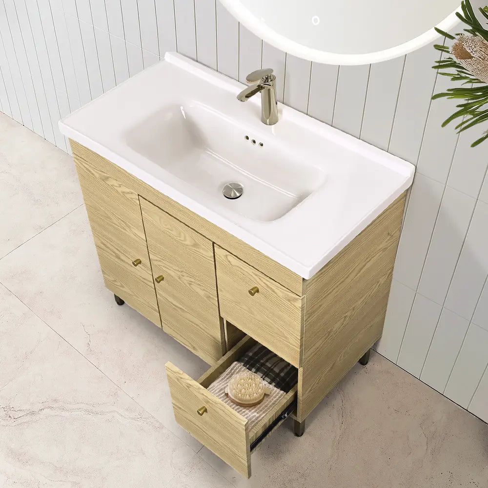 Bathroom vanity with wooden cabinet and white countertop, featuring a sink and open drawer.
