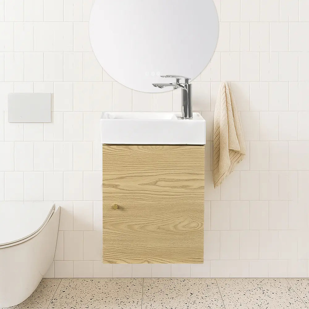 Bathroom with wooden vanity, white sink, and towel.