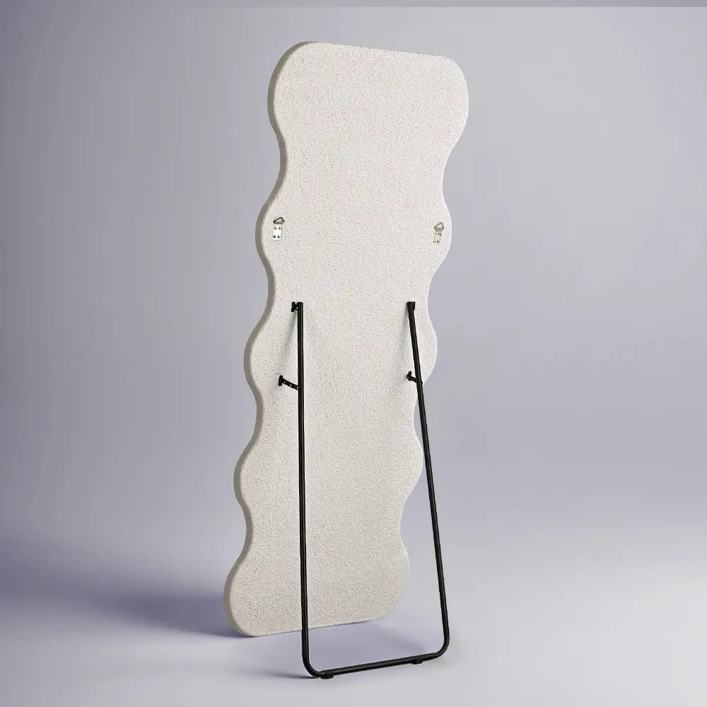 Contemporary full-length mirror with wavy edge in a bright room back view