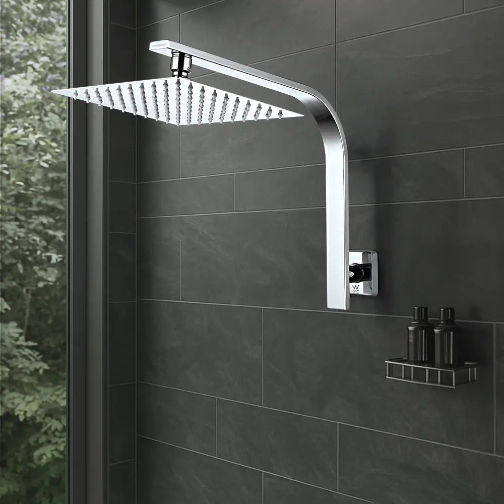 Chrome shower head mounted on a tiled wall with bottles on a shelf.