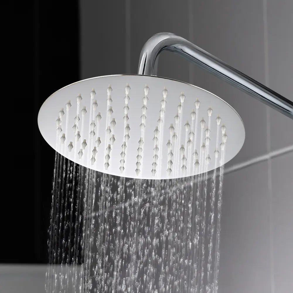 Round chrome rainfall shower head with water spray jets in use