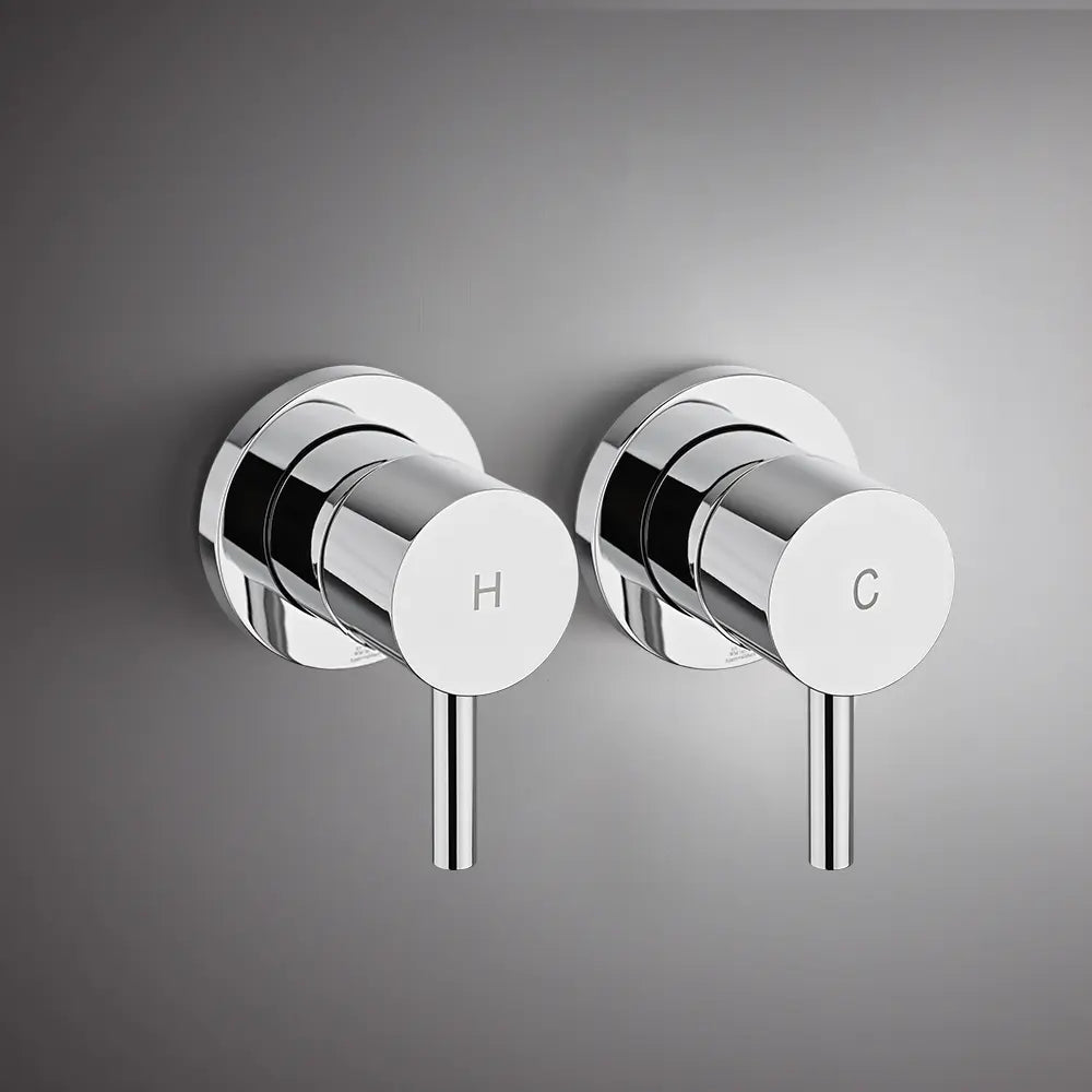 Wall-mounted chrome round shower mixer valve handles with hot and cold indicators on modern grey bathroom wall