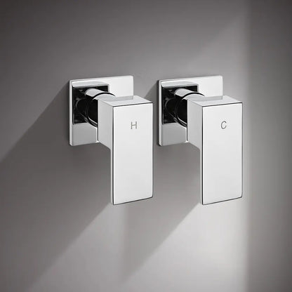 Wall-mounted chrome shower mixer valve handles with hot and cold indicators installed on grey bathroom wall