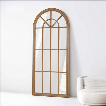 Arch-shaped mirror with wooden frame on a white wall